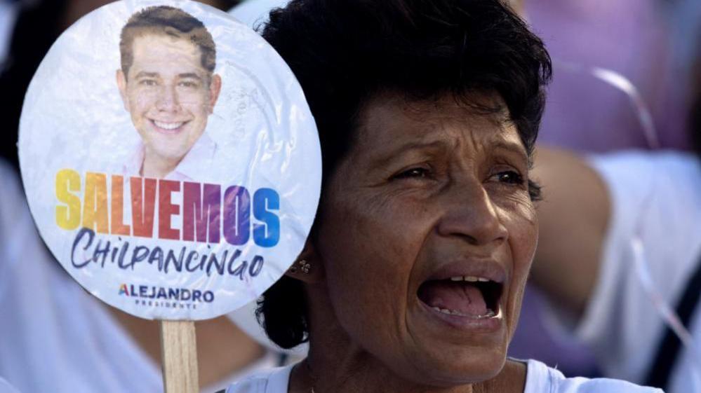 A woman taking part in a protest after the killing of Alejandro Arcos in Chilpancingo holds up a sign bearing the mayor's photograph, reading "Salvemos Chilpancingo", Spanish for "Let's rescue Chilpancingo". 