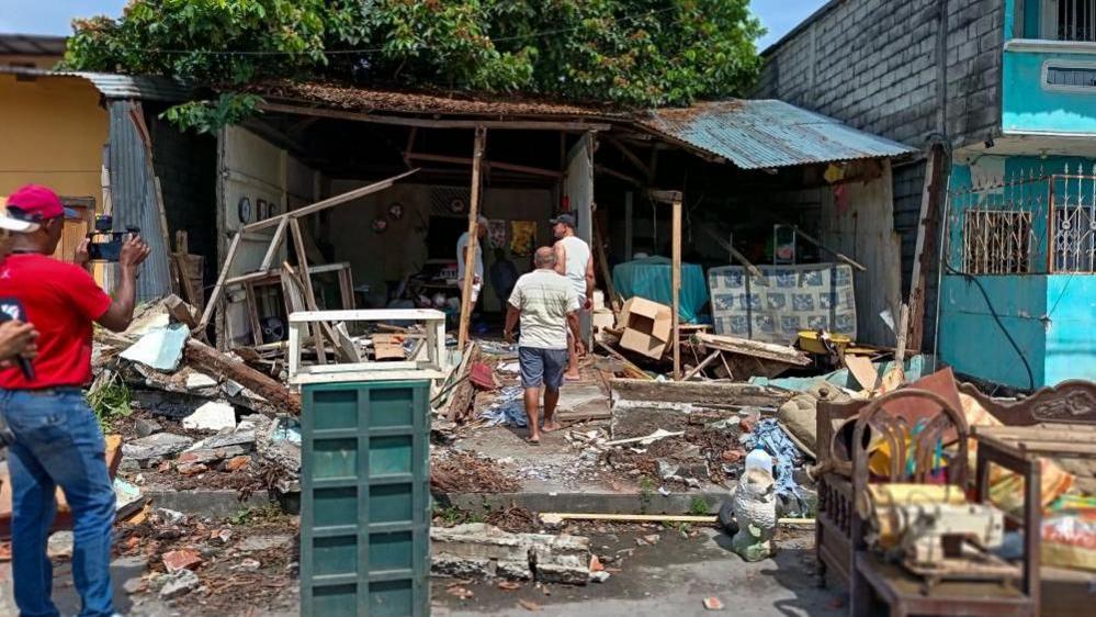 People look at the damage done to a house which is completely open from the front after the earthquake.