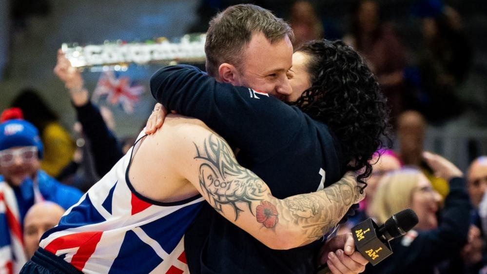 Army veteran James Cairns hugs his partner Hannah Wild in front of a crowd of spectators