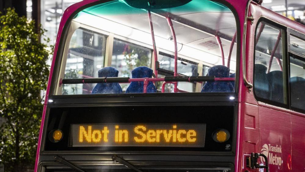 A pink metro bus, zoomed in on the screen which says 'Not In Service.' 