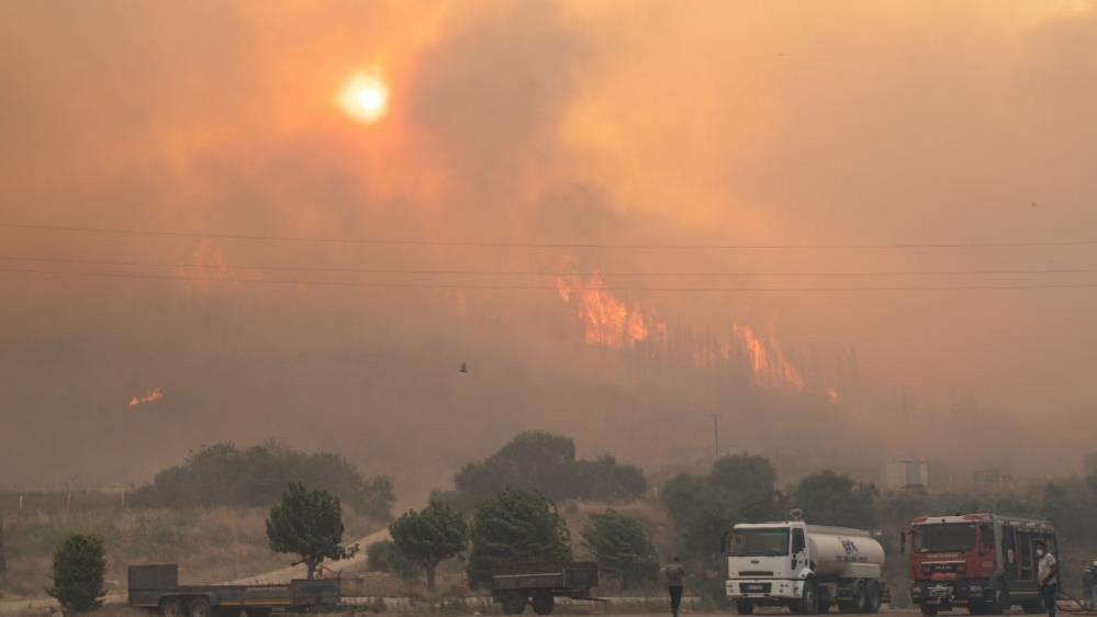 Flames can be seen through smoke on a hillside in the Seferihisar district of Izmir