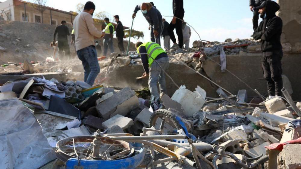 A group of men search through rubble following a strike in the town of Al-Ain in the Baalbek region on Wednesday. In the foreground of the image is a child's bike.