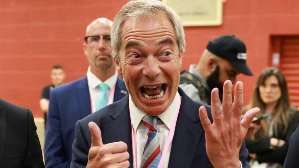 Nigel Farage holds up six fingers as he grins widely