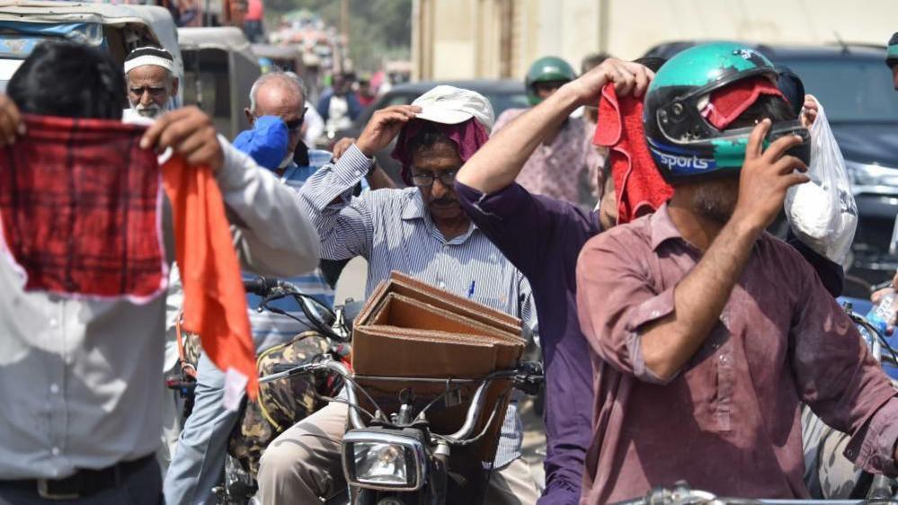 People cover their heads in wet towels during a heatwave in Karachi, Pakistan