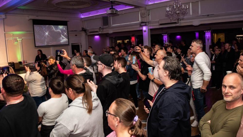 Fans standing and holding phones