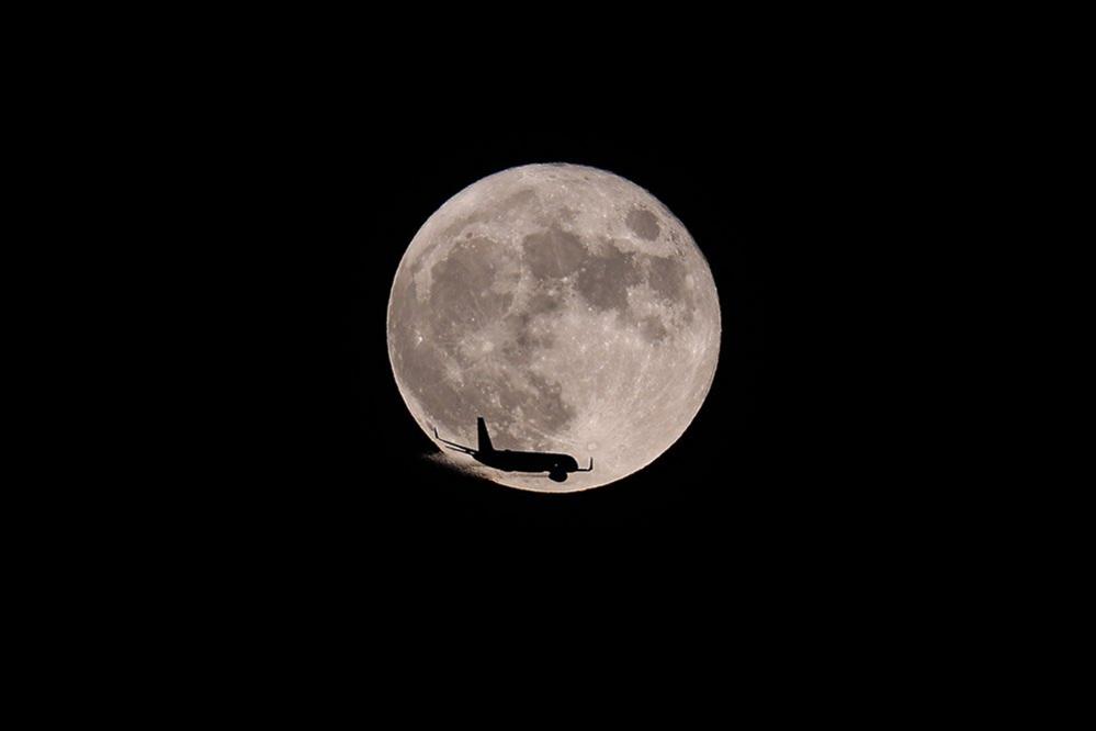 A plane passes in front of the moon