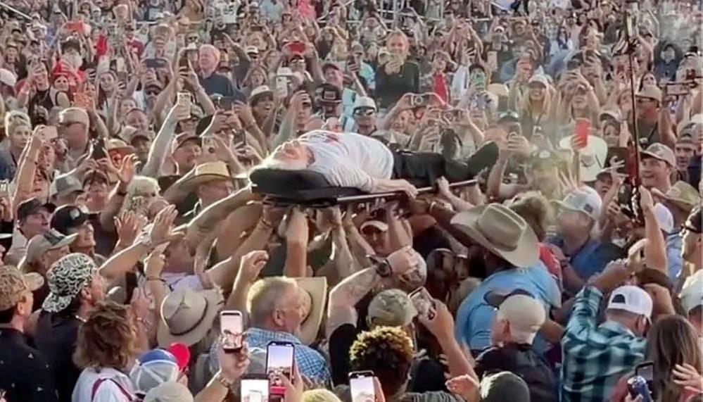 Pauline Kana lies on a stretcher and is passed from person to person at a concert.