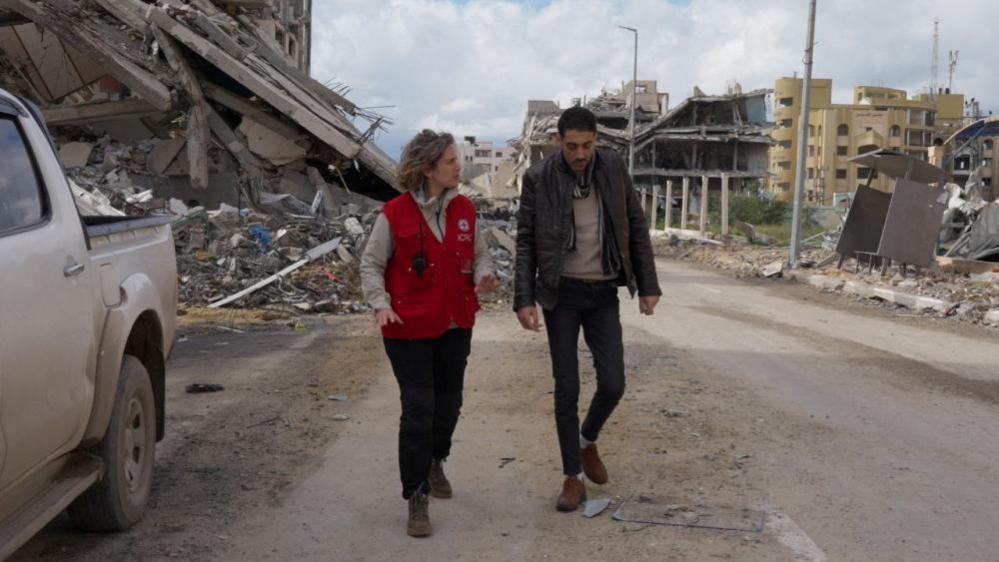 Image shows Hisham al-Sayed walking with a member of the Red Cross as he is released by Hamas 