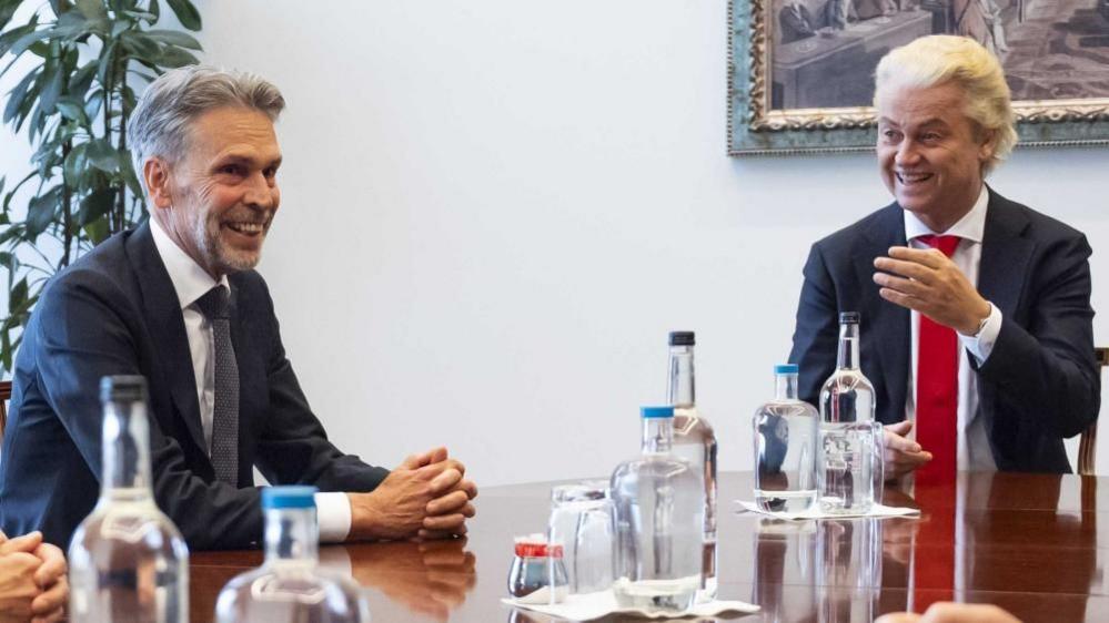 Former intelligence service chief Dick Schoof (L) sits next to Party for Freedom (PVV) leader Geert Wilders