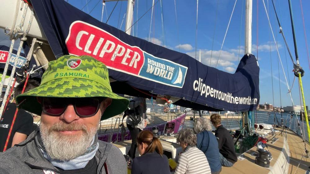 Bob Brown on a racing yacht with other people sat in the background.