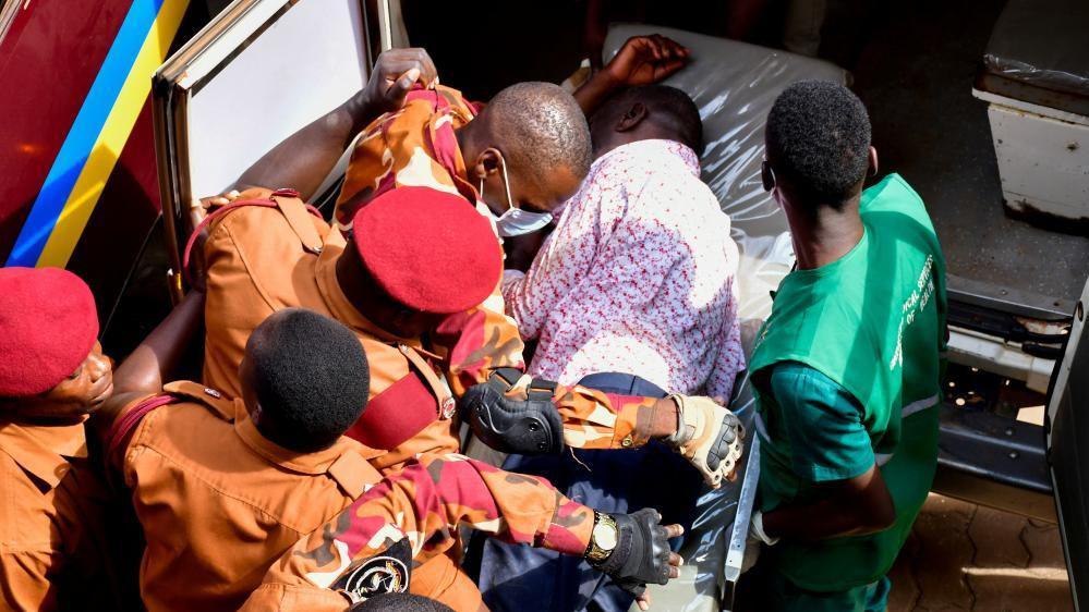 Kizza Besigye is put in an ambulance by uniformed prison guards 