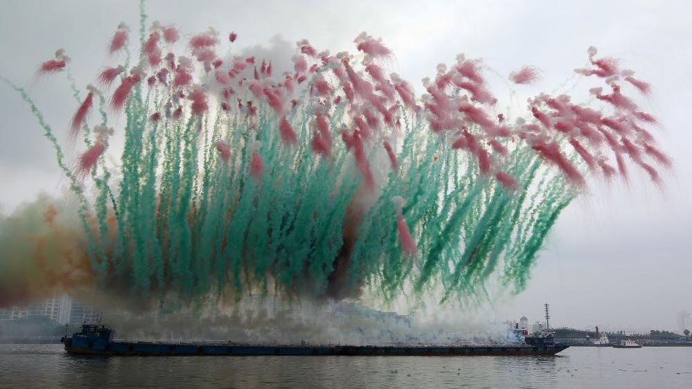 People watch a fireworks presented by Chinese artist Cai Guo-Qiang during day time near Huangpu river on August 8, 2014 in Shanghai, China.