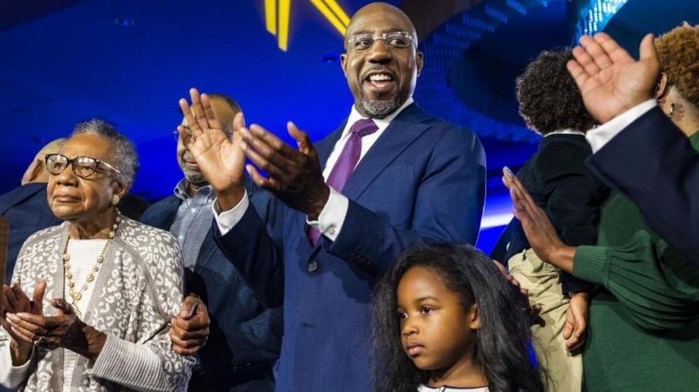 US Democratic Senator Raphael Warnock (C) celebrates after he was reelected to the Senate in Atlanta, Georgia