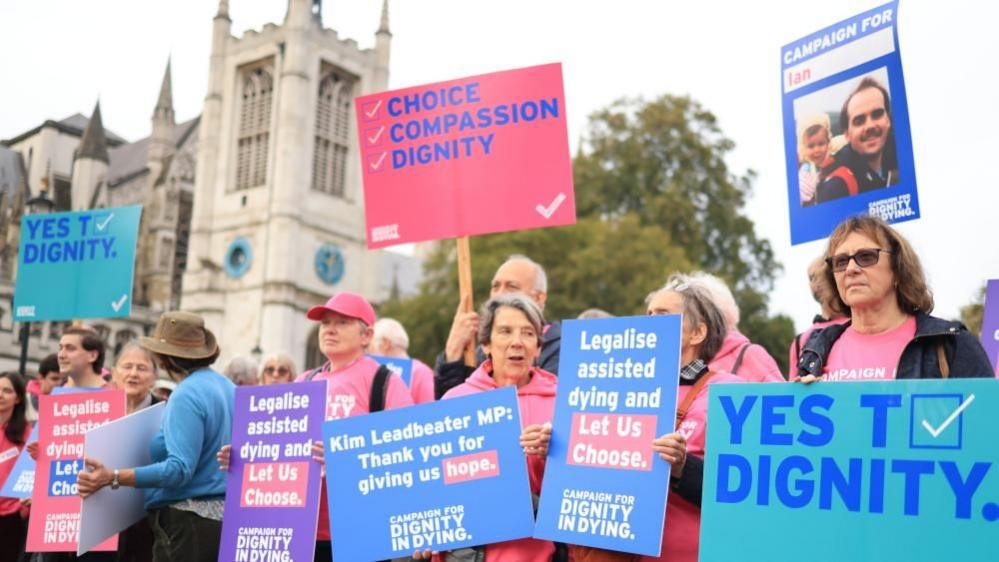 People holding protest signs in support of assisted dying 