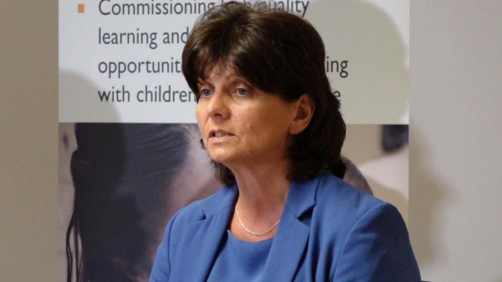 Joyce Thacker, pictured in a blue dress and jacket, with shoulder length brown hair