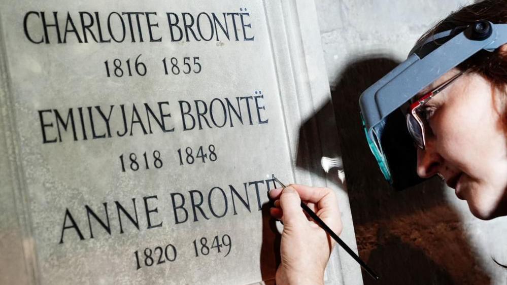 Conservator Lucy Ackland adds the finishing touches to the memorial to Charlotte, Emily and Anne Bronte at Poets' Corner in Westminster Abbey in London