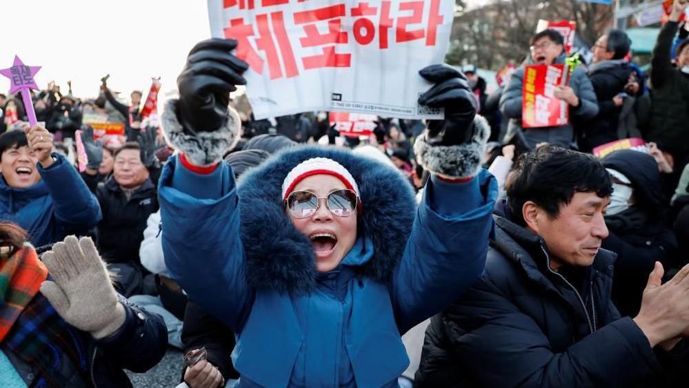 People in South Korea celebrate after parliament passes a motion to impeach President Yoon Suk Yeol