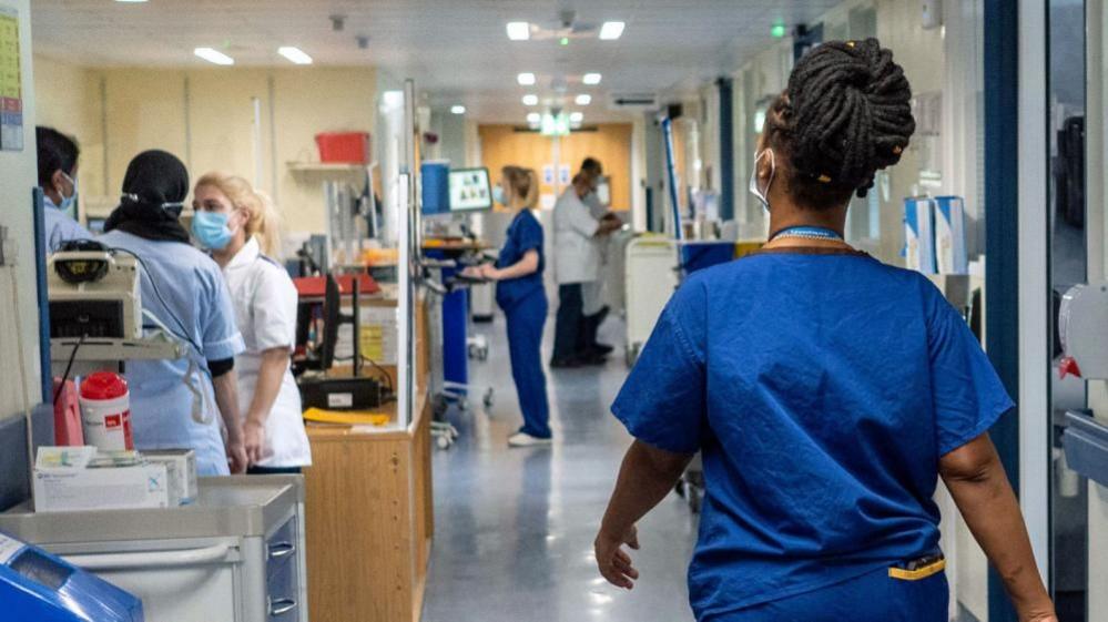 A nurse walks along a corridor in an NHS hospital.