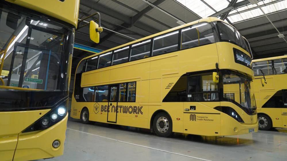 Three yellow Bee Network double-decker buses are parked next to each other in a depot.