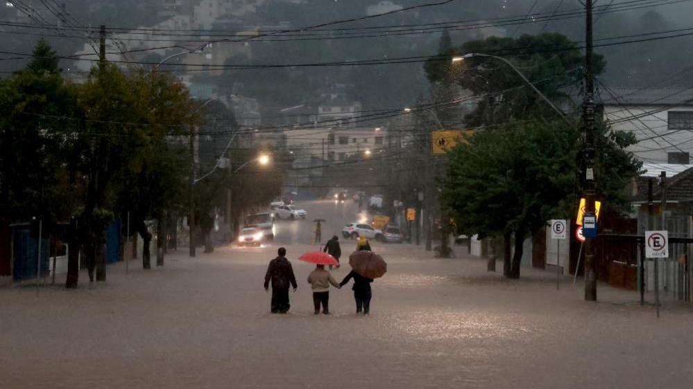 People walk in a flooded area in the Cavalhada neighbourhood after heavy rains in Porto Alegre, Brazil May 23, 2024.