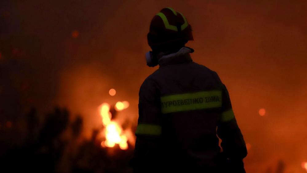 A firefighter works at the scene of a wildfire in Ierapetra, on Crete island, Greece