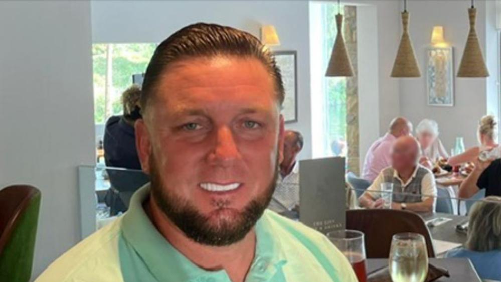 A man in a lime green top. His teeth have been whitened and his hair is slicked back. 