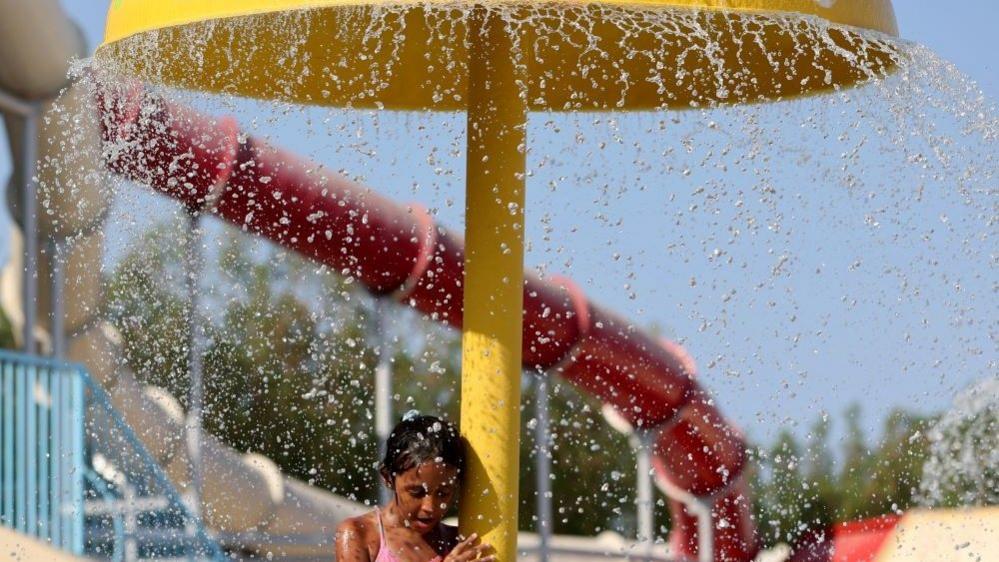 An image of a young girl cooling off under a water fountain at a a Red Sea resort in Hurghada, Egypt July 30, 2024.