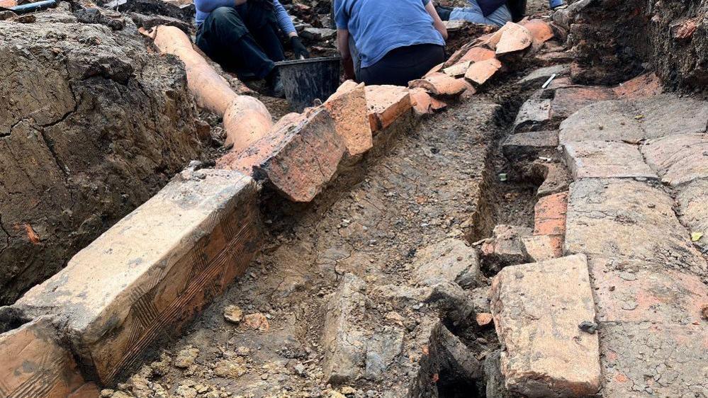 An excavation area showing Roman tiles running together along the floor like a tube