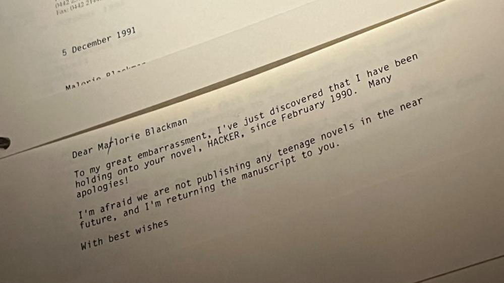 Picture of a letter dated 5 December 1991, which reads: 
Dear Marlorie (with a crossed out 'r') Blackman
To my great embarrassment, I've just discovered that I may have been holding onto your novel, HACKER, since February 1990. Many apologies! I'm afraid we are not publisihing any teenage novels in the near future, and I'm returning the manuscript to you. With best wishes.