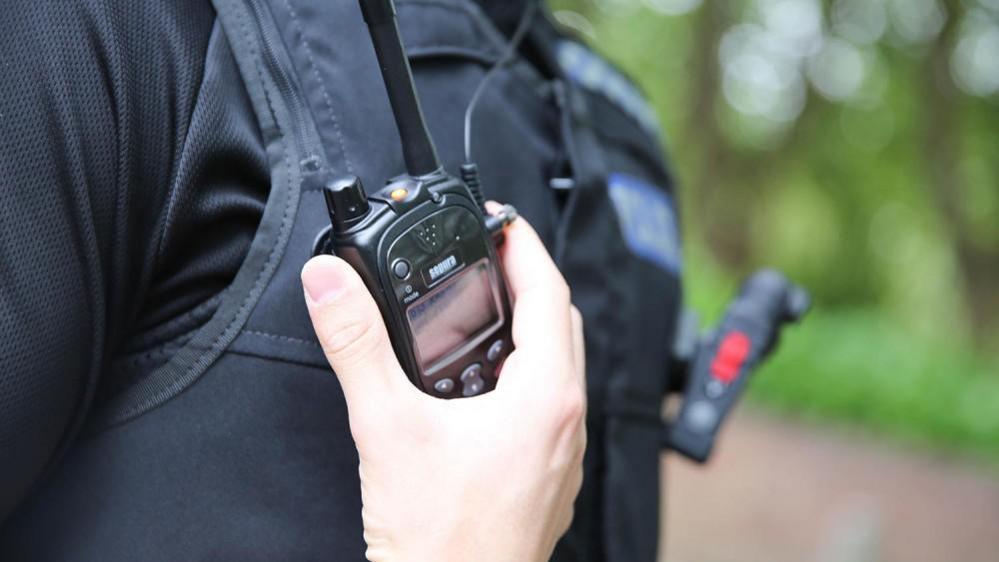 Police officer with hand on attached radio