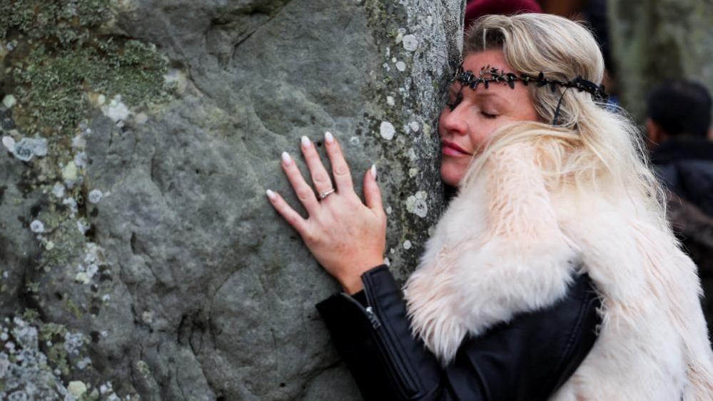 A woman wearing fur hugging the stones