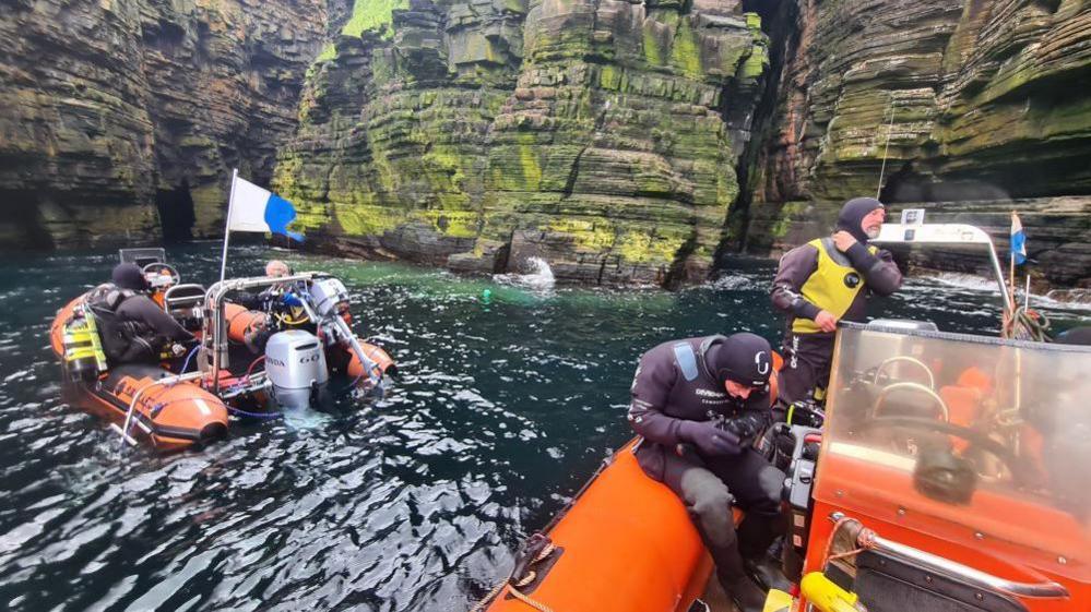 Divers and an inflatable boat at sea cliffs