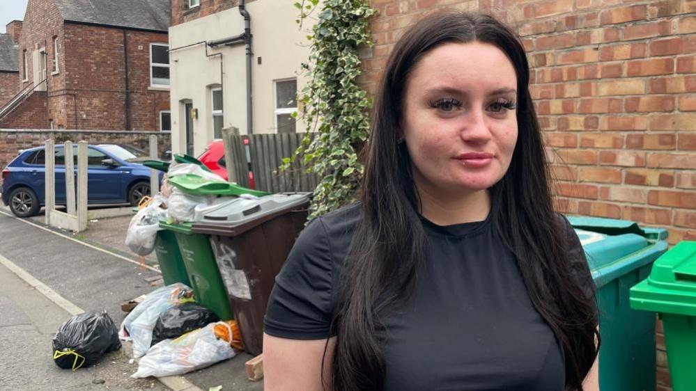 Emily Pellicci stood on Lawson Street, with overflowing bins and rubbish in the background.