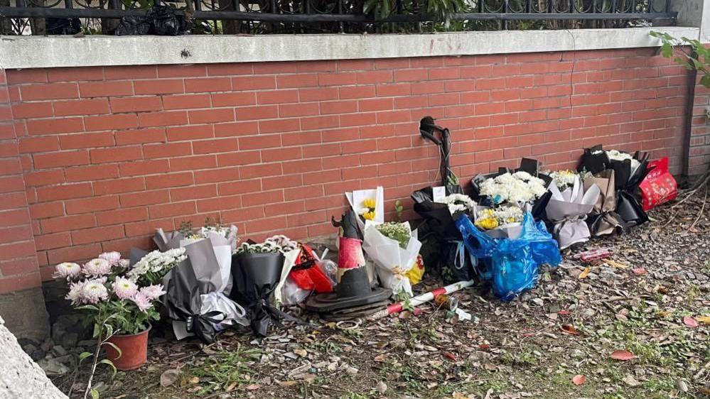 Floral tributes are placed near an entrance to the Wuxi Vocational College of Arts and Technology following a knife attack, in Wuxi, Jiangsu province