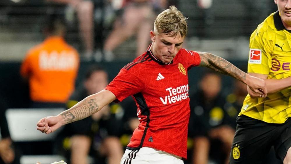 Brandon Williams photographed playing for Manchester United against Borussia Dortmund. He is wearing United's red shirt with black trim.