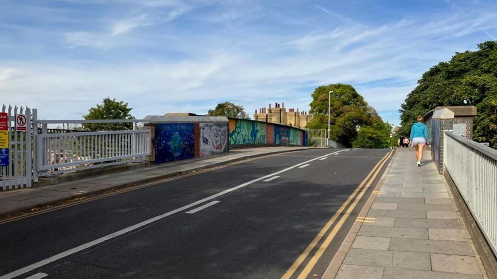 The Mill Road bridge over the railway in Cambridge with people walking along one of its pavements