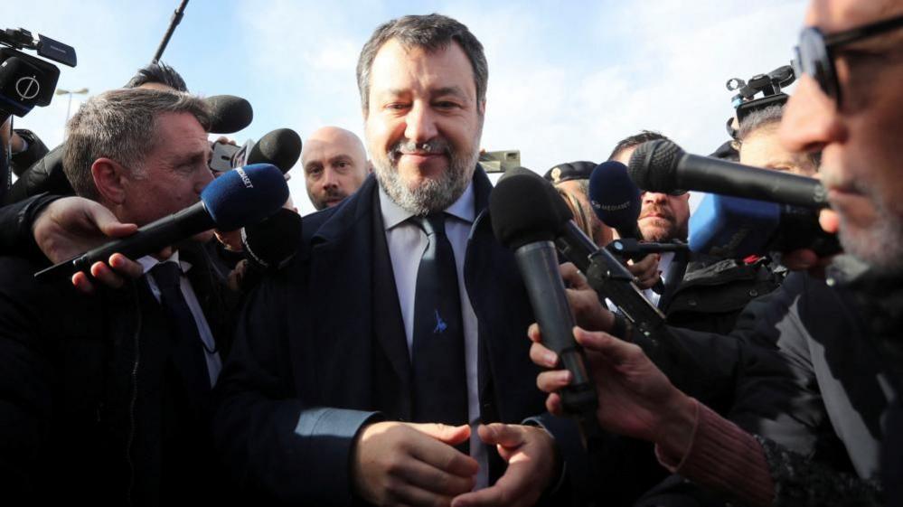 Matteo Salvini arrives at a court in Sicily where he is surrounded by reporters ahead of a verdict in a long-running trial