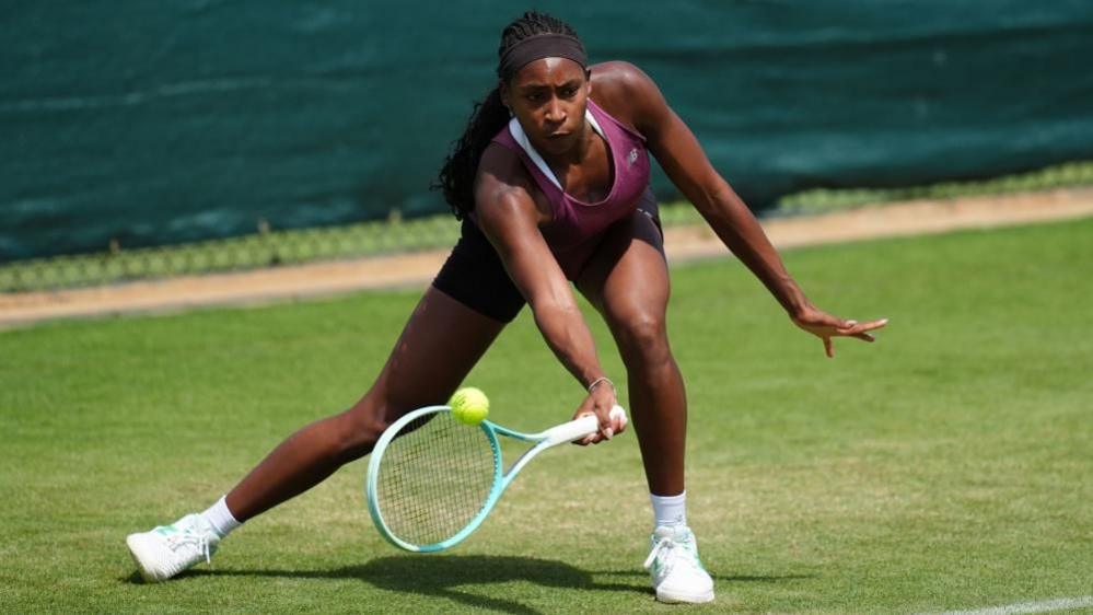 Tennis player Coco Gauff is seen hitting a ball with an underhand during a practice session ahead of Wimbledon, as the sun shines on her
