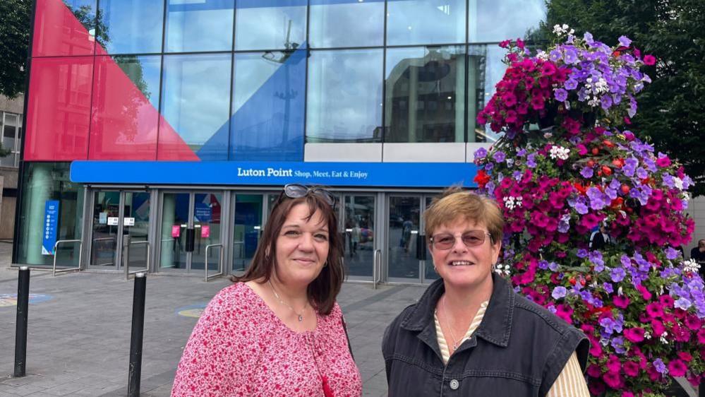 Two women standing in front of the rebranded shopping centre