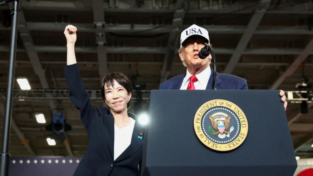 US President Donald Trump speaks to US Navy sailorin Japan, as Japanese Prime Minister Sanae Takaichi gestures alongside him
