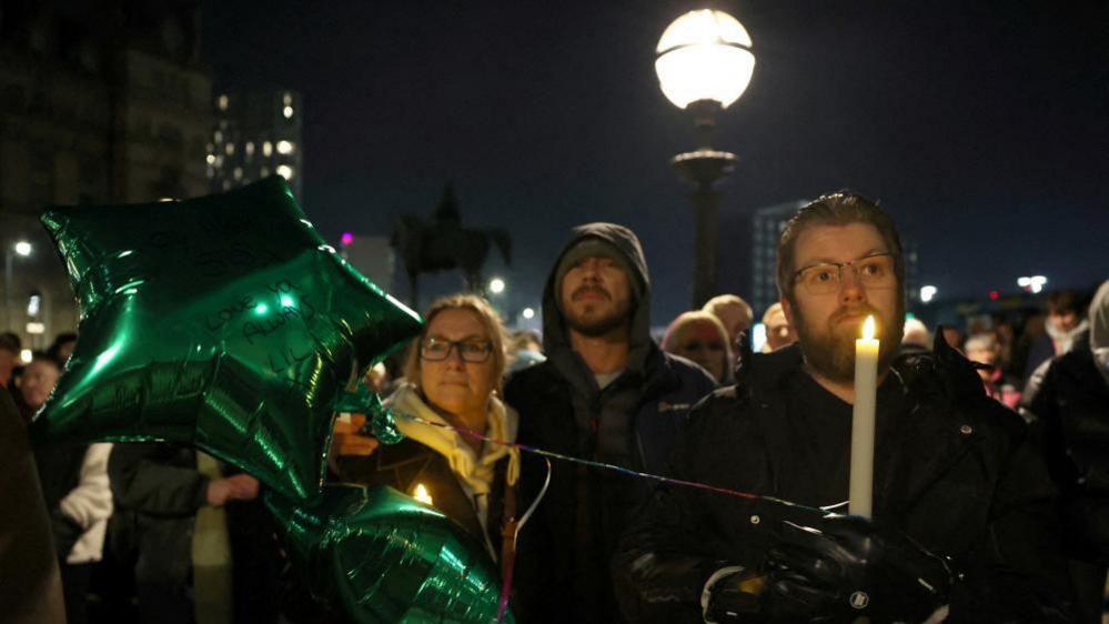 Image shows people attending a vigil for James Lee Williams, popularly known as The Vivienne, in Liverpool, Britain, on 12 January, 2025
