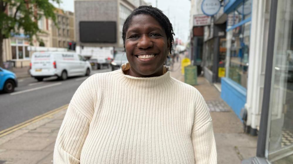 Dorothy Koomson stands on the street smiling for the camera.