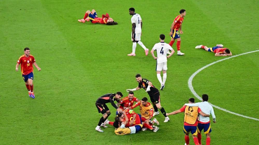 Spanish players celebrate on the pitch after winning the Euros 2024 final. England players are also seen walking around and looking dejected.