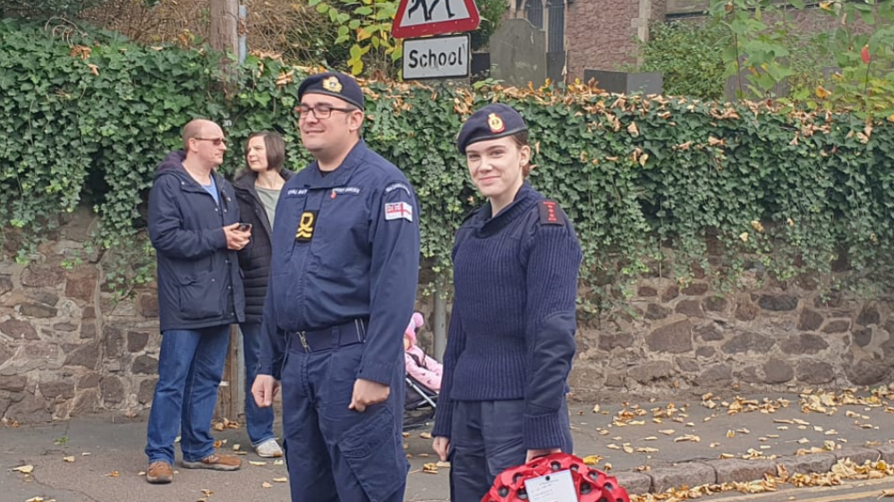 Two sea cadets pictured out in the street, one is pictured with a poppy wreath
