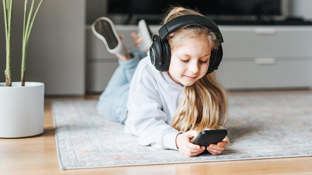 Child using a phone with headphones