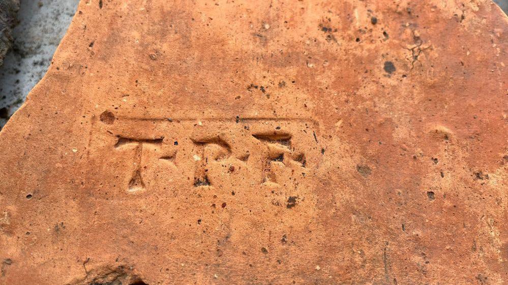 Terracotta coloured tile with TPF brand in it