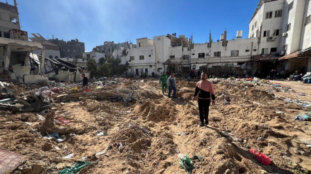 Palestinians inspect damages following an Israeli raid at Kamal Adwan hospital, in the northern Gaza Strip