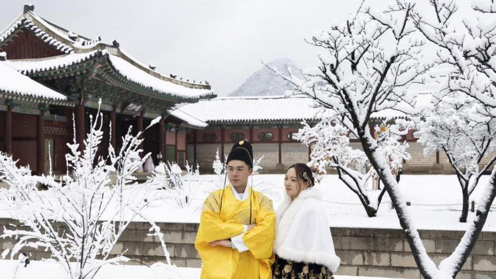 Thai tourists wearing Korean traditional Hanbok dresses take pictures amid snowfall at the Gyeongbokgung Palace in Seoul, South Korea, 27 November 2024.