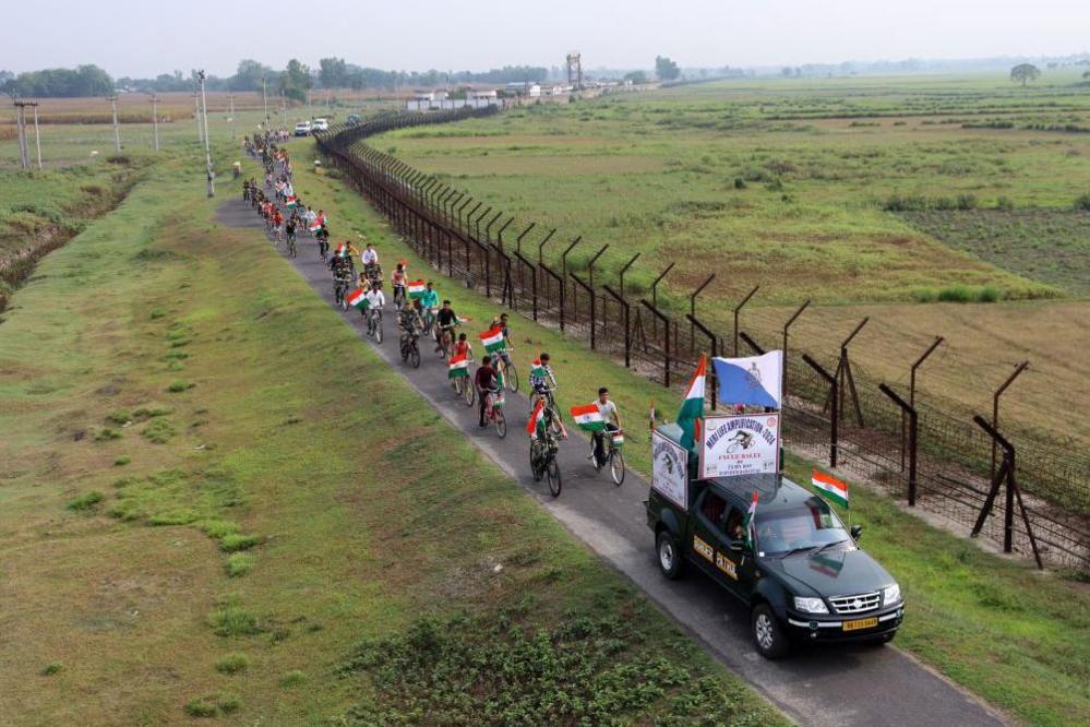 Indian Border Security Force (BSF) personnel, along with the youths, are taking part in a cycle awareness rally at the India-Bangladesh border in Pariyal village near Raiganj, in North Dinajpur district of West Bengal, on May 14, 2024