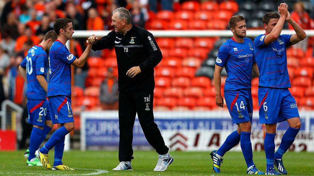 Terry Butcher dressed in black training gear congratulates his Inverness players after a match in 2013